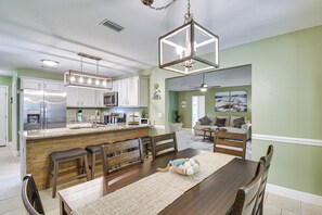 Een moderne keuken met een centraal eiland, een houten eettafel en barkrukken.