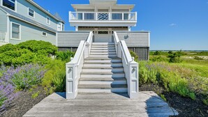 Une maison à deux étages dotée d’un balcon, d’un escalier menant à l’entrée et offrant une vue sur le paysage environnant.