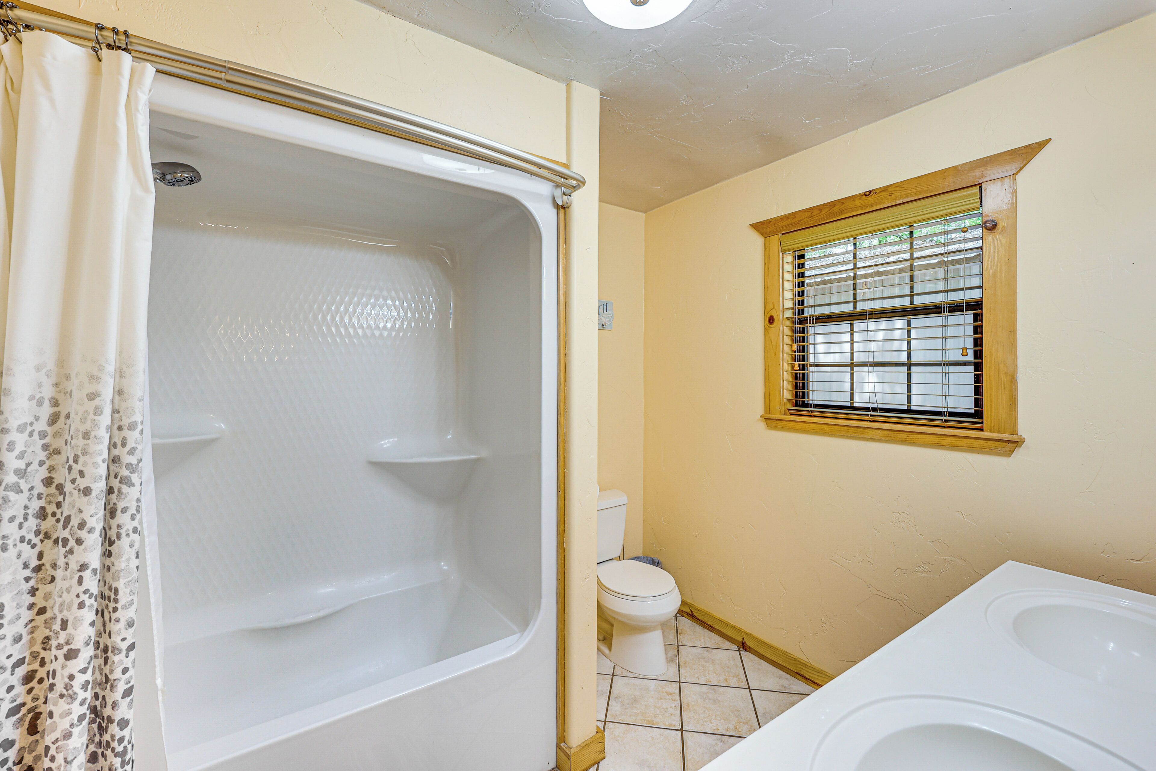 A bathroom with a bathtub, toilet, and window.