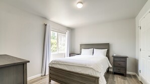 Una camera da letto con un letto in legno, un comodino, una cassettiera e una finestra con tende.