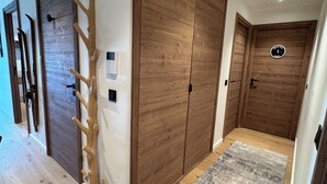 A hallway with wooden doors, a coat rack, and a textured rug.