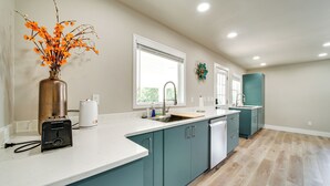 A modern kitchen with teal cabinets, a white countertop, and a vase of orange flowers. - 3 Mi to Dtwn: Family Home w/ Garden & EV Charger (Yakima)