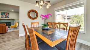 A dining area with a rectangular table, six wooden chairs, a chandelier, a mirror, and a window with a view of houses. - 3 Mi to Dtwn: Family Home w/ Garden & EV Charger (Yakima)