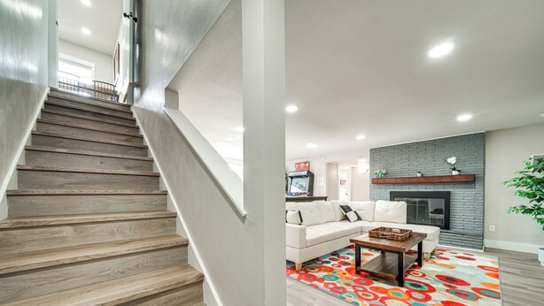 A staircase with wooden steps leading to a living area with a white sofa, a fireplace, and a colorful rug. - 3 Mi to Dtwn: Family Home w/ Garden & EV Charger (Yakima)