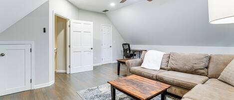Amplia sala de estar con una mesa de centro de madera, un sofá color beige y un ventilador de techo.