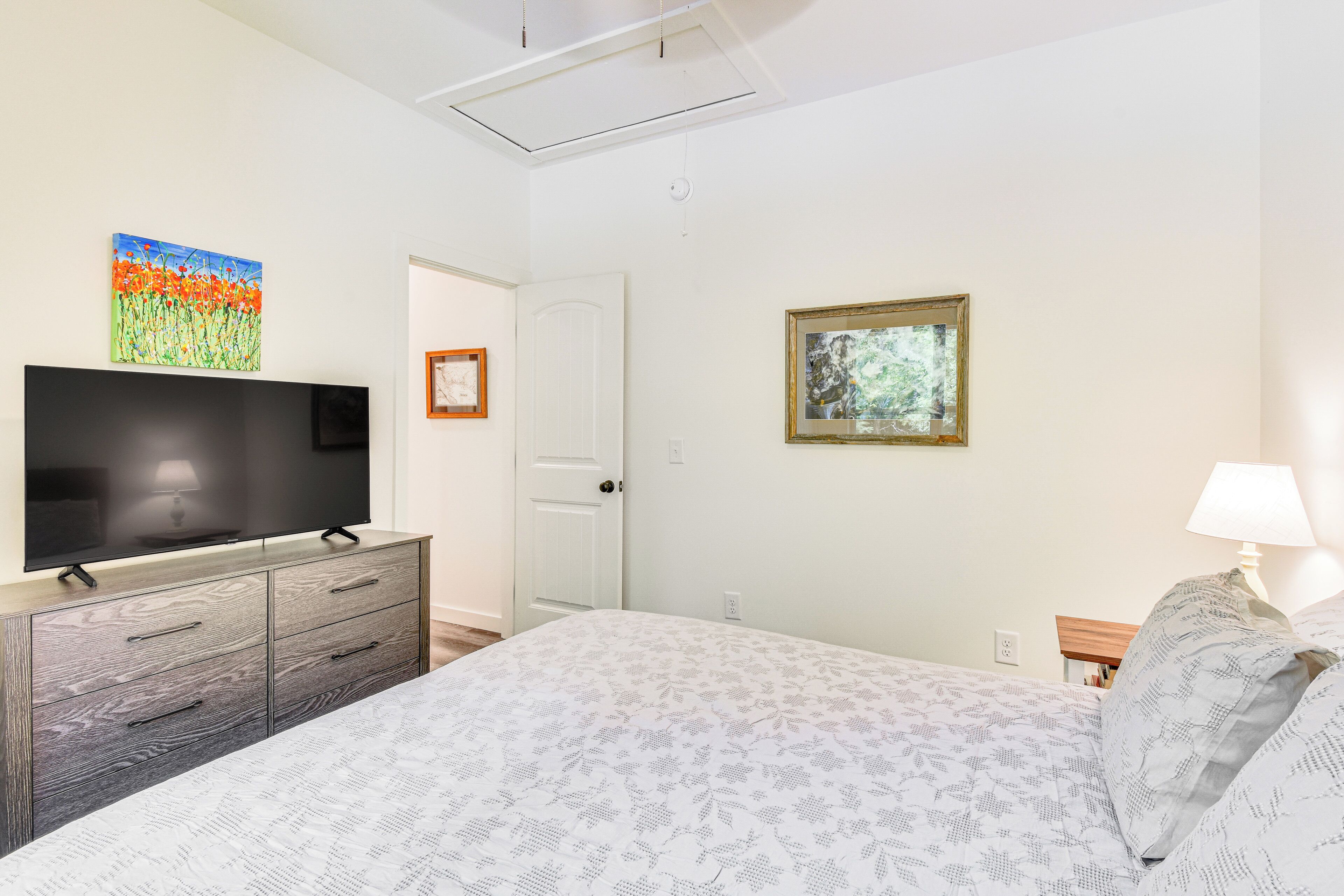 Ein Schlafzimmer mit einem Bett, einem Fernseher auf einer Kommode und zwei Bildern an der Wand.