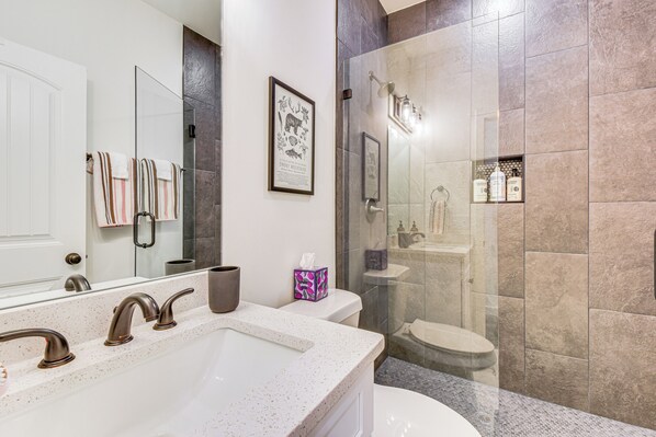 A modern bathroom with a large mirror, a freestanding bathtub, a glass-enclosed shower, and a toilet. - Hike, Golf & Swim: Blue Ridge Cabin Escape (Clayton)