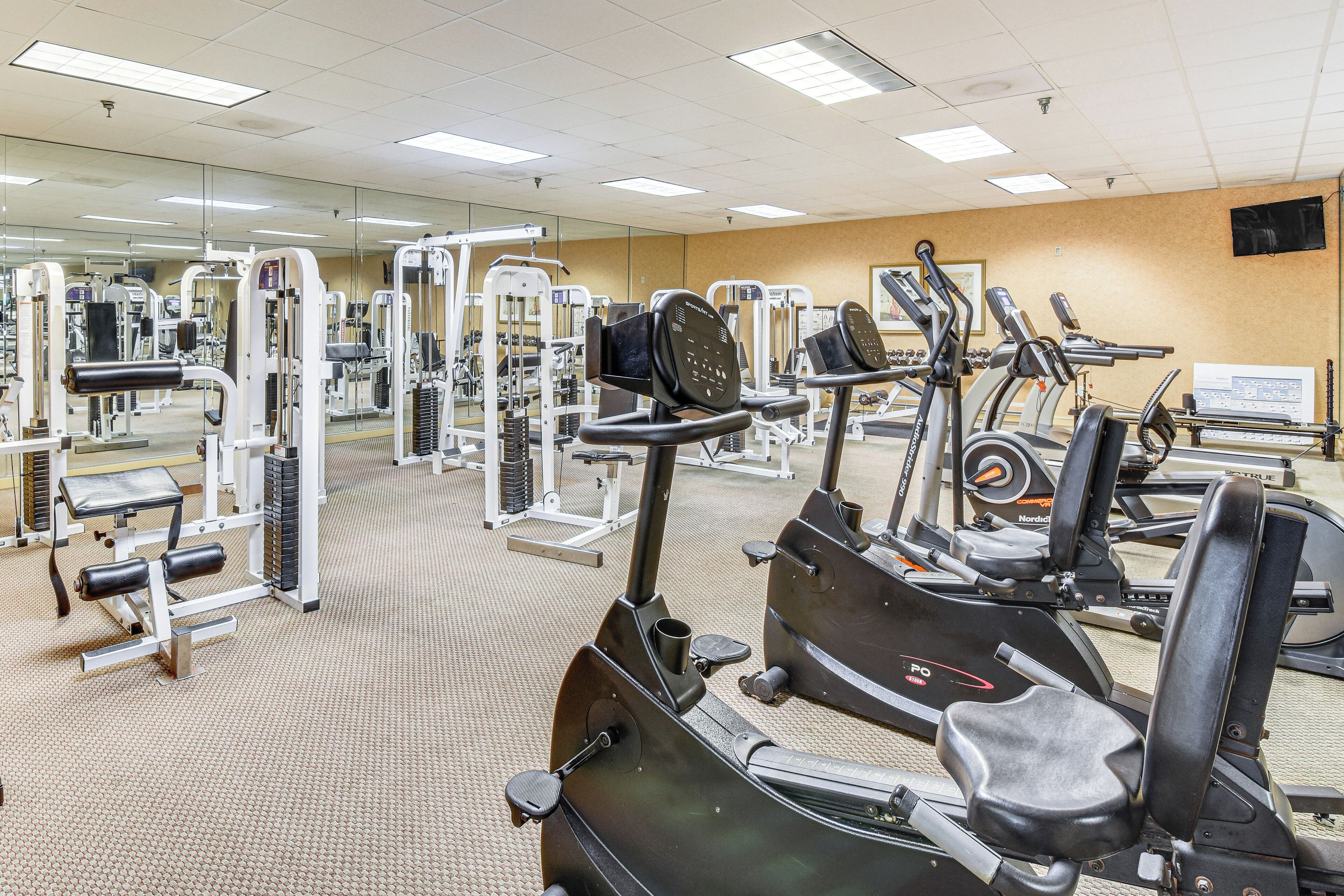 Un gimnasio con diversas máquinas de ejercicio, espejos y un panel de control.