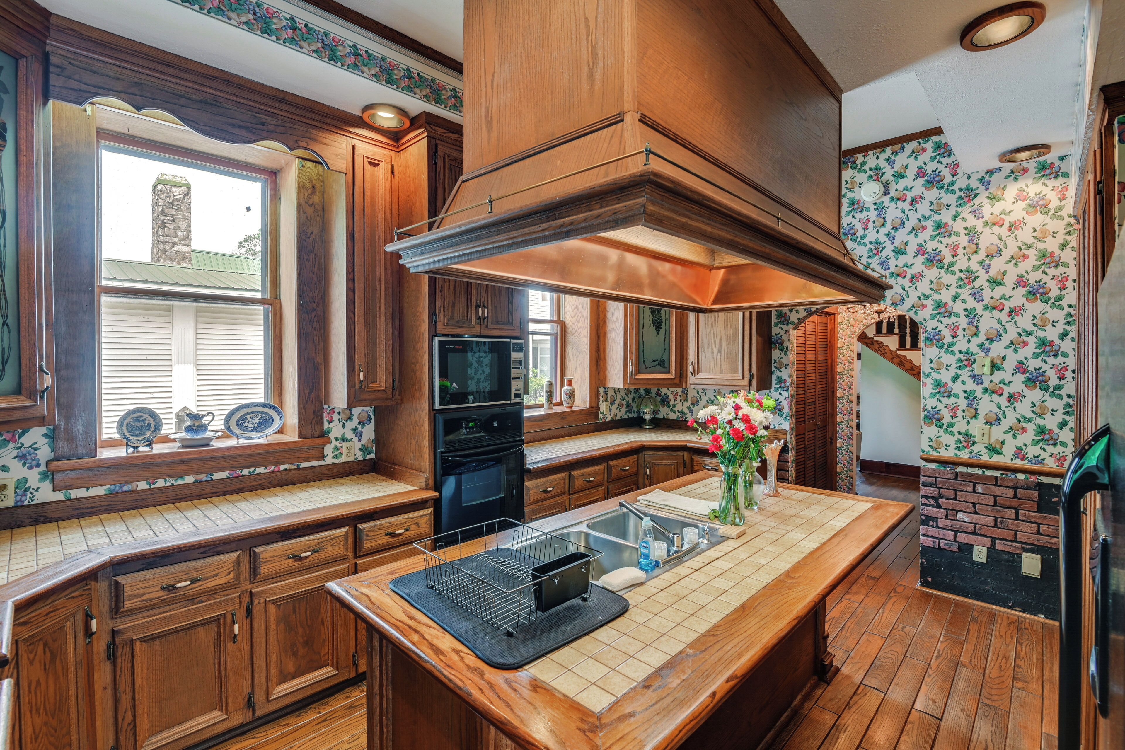 A kitchen with wooden cabinets, a central island, a stove, and a large window.