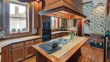 A kitchen with wooden cabinets, a central island, a stove, and a large window.