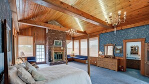 Une chambre spacieuse avec un grand lit, une cheminée, un banc et une commode.