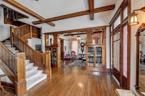 A spacious foyer with a wooden staircase, a large bookcase, and a chandelier. - Walk to Lawrenceburg Square: Home for Large Groups (Lawrenceburg)
