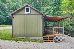 A small, single-story wooden shed with a porch and a fenced area. - 1 Mi to Lake: Charming Byrdstown Retreat w/ Deck! (Byrdstown)