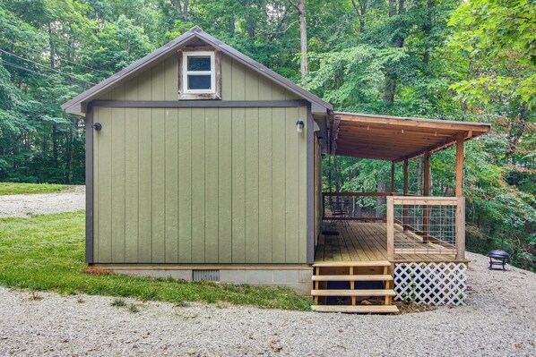 A small, single-story wooden shed with a porch and a fenced area. - 1 Mi to Lake: Charming Byrdstown Retreat w/ Deck! (Byrdstown)