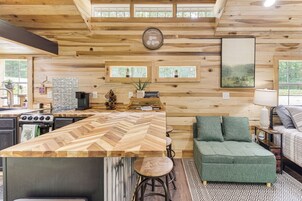 Interior de madera con cocina, comedor y un sofá verde.