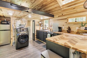 A modern kitchen with wooden cabinetry, a built-in oven, and a large island with a herringbone countertop. - 1 Mi to Lake: Charming Byrdstown Retreat w/ Deck! (Byrdstown)