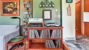 A cozy room with a wooden record player, a bookshelf filled with vinyl records, and a framed picture on the wall. - Peaceful Country Retreat: Private & Convenient (Frenchtown)