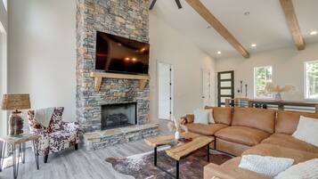 A living room with a stone fireplace, leather sofa, and a television mounted on the wall.