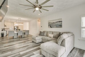 A modern living room with a sectional sofa, a dining area with a table and chairs, and a kitchen in the background. - Walk to Mississippi River: Grafton Townhome! (Grafton)
