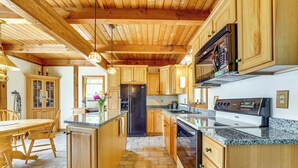 Una cocina con gabinetes de madera, encimeras de granito, un refrigerador de acero inoxidable y un horno empotrado.