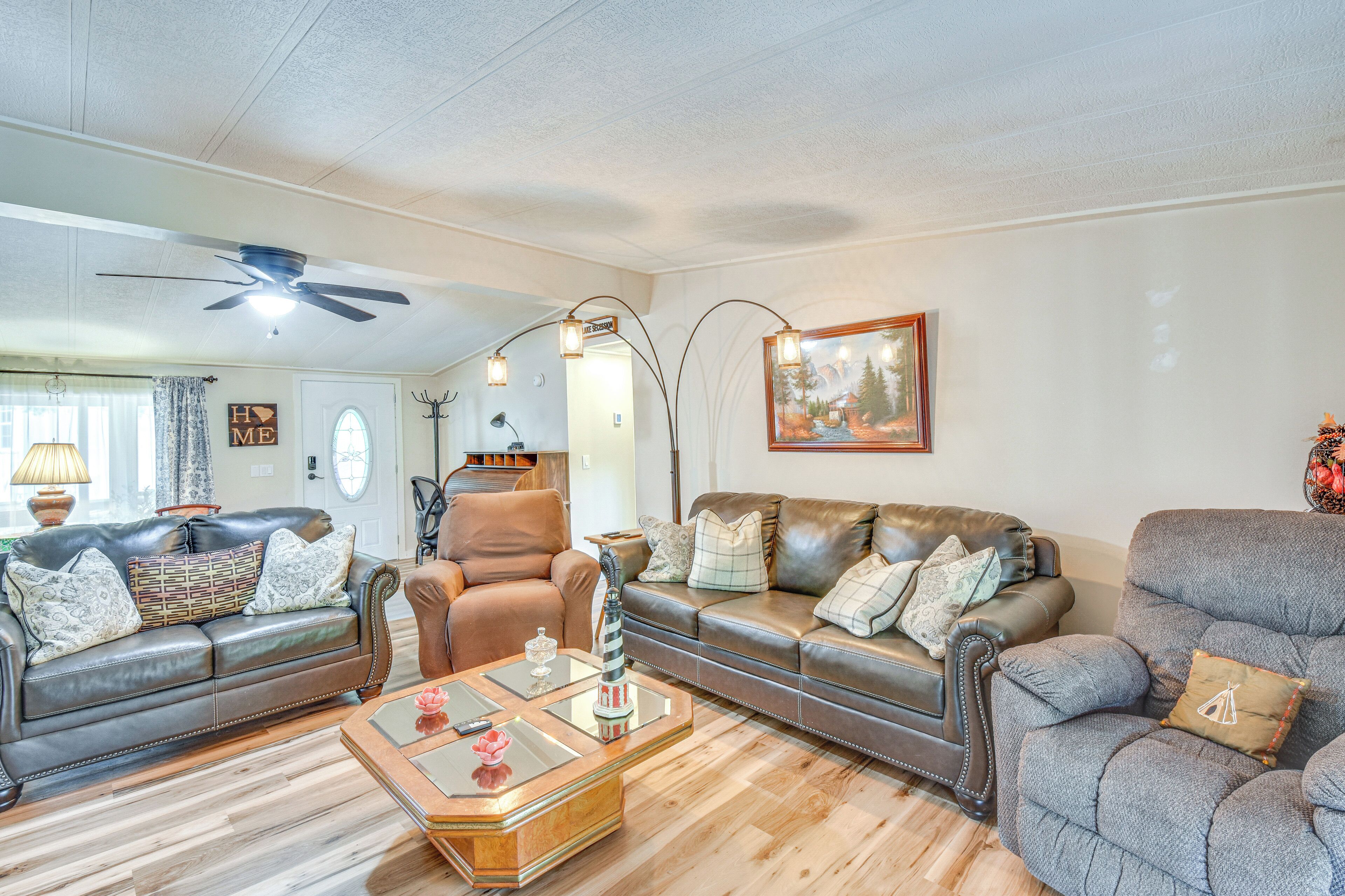 A living room with leather sofas, a coffee table, and a ceiling fan.