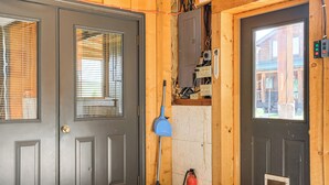 Eine Holztür mit Fenster, ein blauer Besen und ein Feuerlöscher.