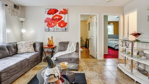 A living room with a grey sofa, a coffee table, and a glass display unit. - 8 Mi to Long Beach: Cozy Apt w/ Fenced Yard! (Baldwin)