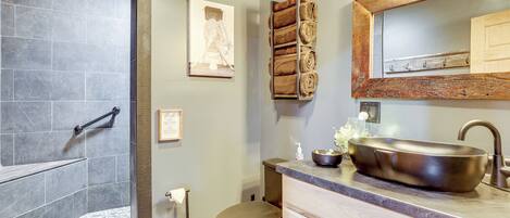 A bathroom with a shower, toilet, sink, and towel rack.