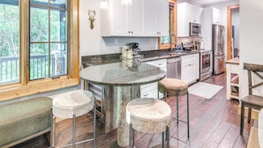 A modern kitchen with a central island, bar stools, and a wooden bench. - Resort Perks, By Lake Glenville: Chinquapin Escape (Glenville)