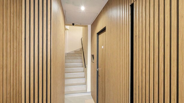 A hallway with wooden paneling, a staircase, and a door. - Appart'hotel Cannes Sun (Cannes)