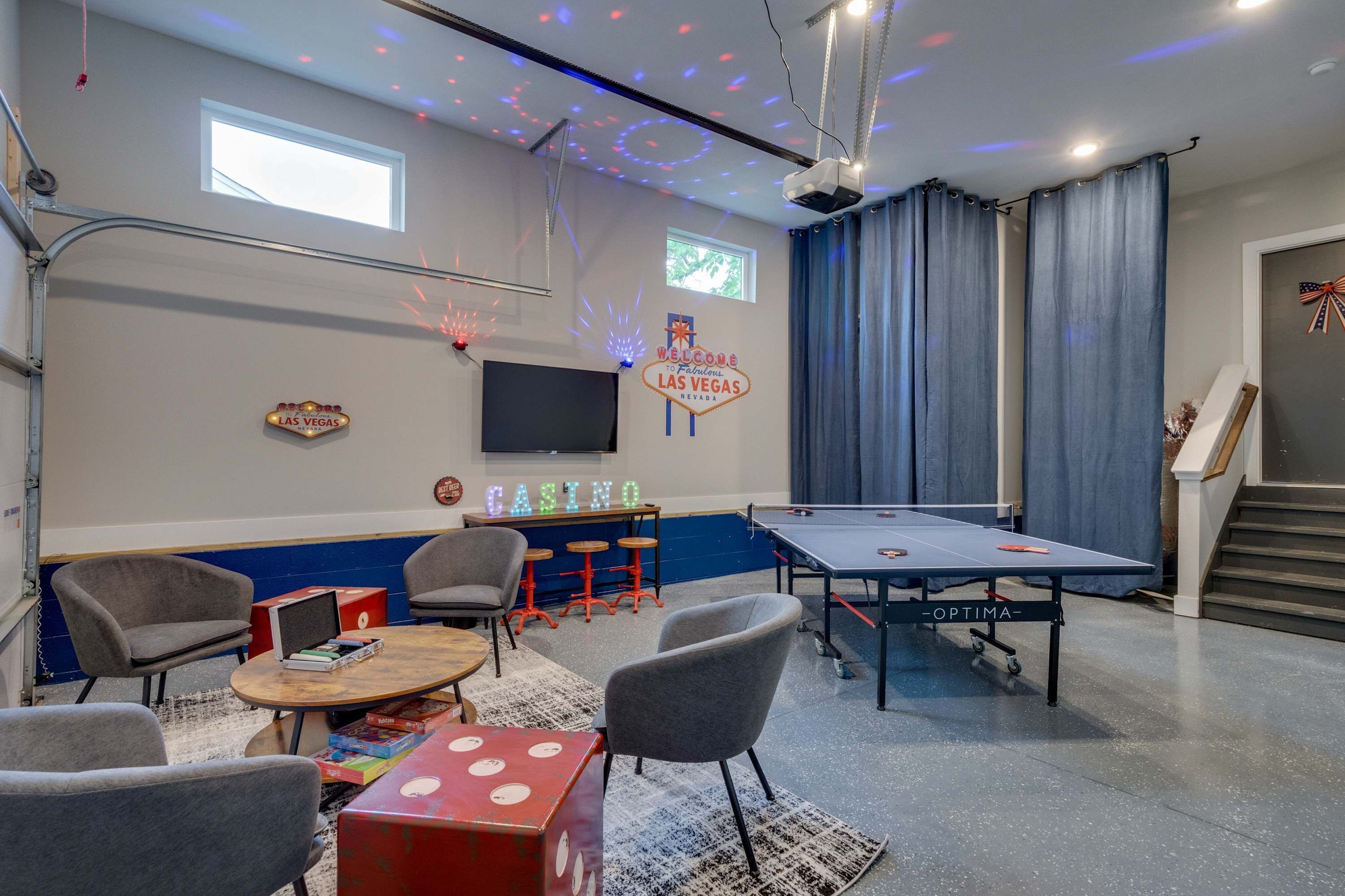 A room with a pool table, gaming chairs, a small bar area, and a TV mounted on the wall.