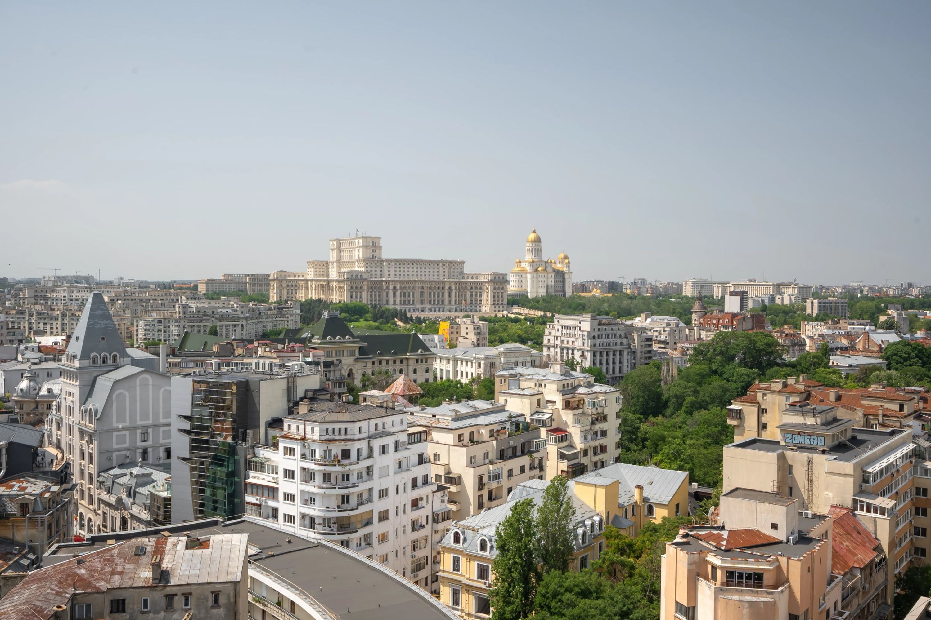 A cityscape with a mix of modern and historic buildings, including a prominent white building with golden domes in the background.