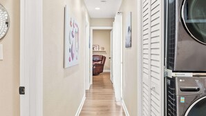 A hallway with a washing machine, a door, and a wall-mounted clock.