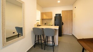 Una cocina compacta con un mueble de madera, un refrigerador negro y dos taburetes grises.