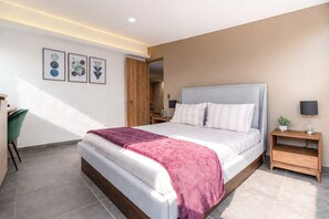 Un dormitorio moderno con una cama grande, un escritorio y una silla.