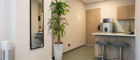 Et moderne køkken med en bar, en potteplante og et spejl på væggen.