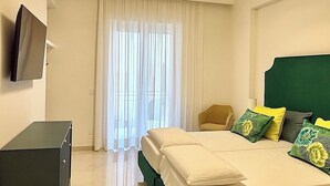 Una habitación de hotel con cama, televisión montada en la pared, escritorio y una silla.