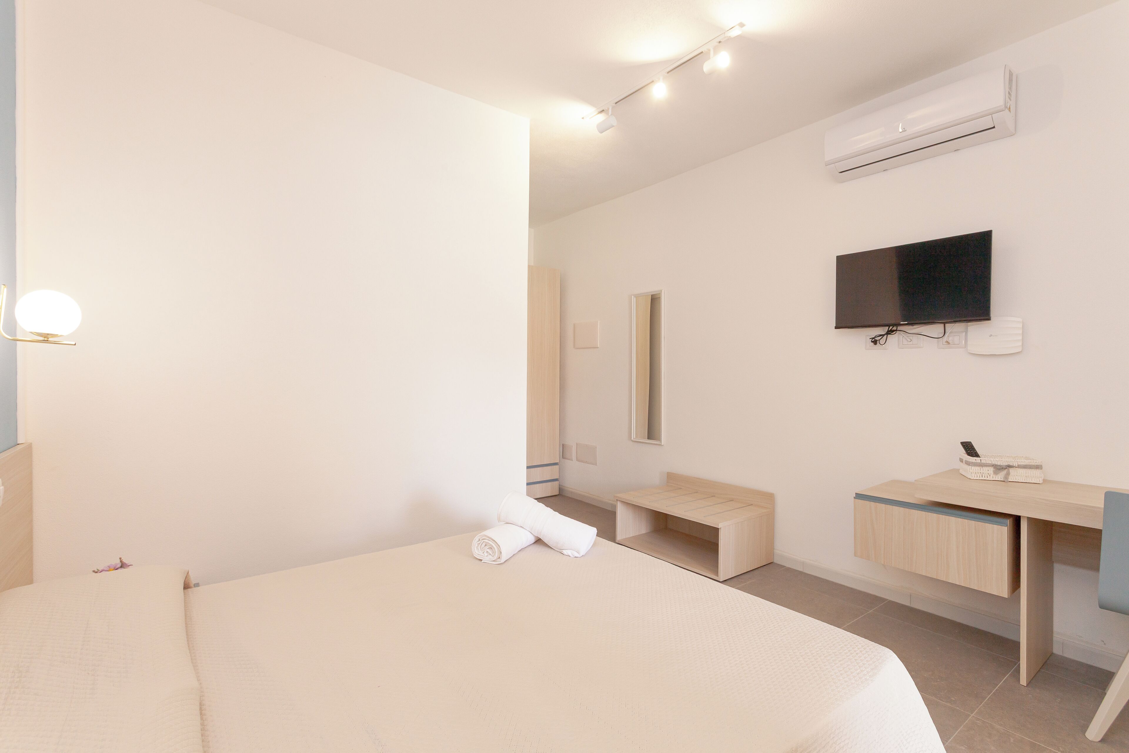 Et moderne hotelværelse med seng, skrivebord, spejl og aircondition.