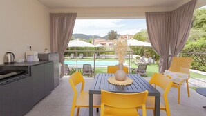 A modern kitchen with a dining area, a pool, and a view of the mountains.