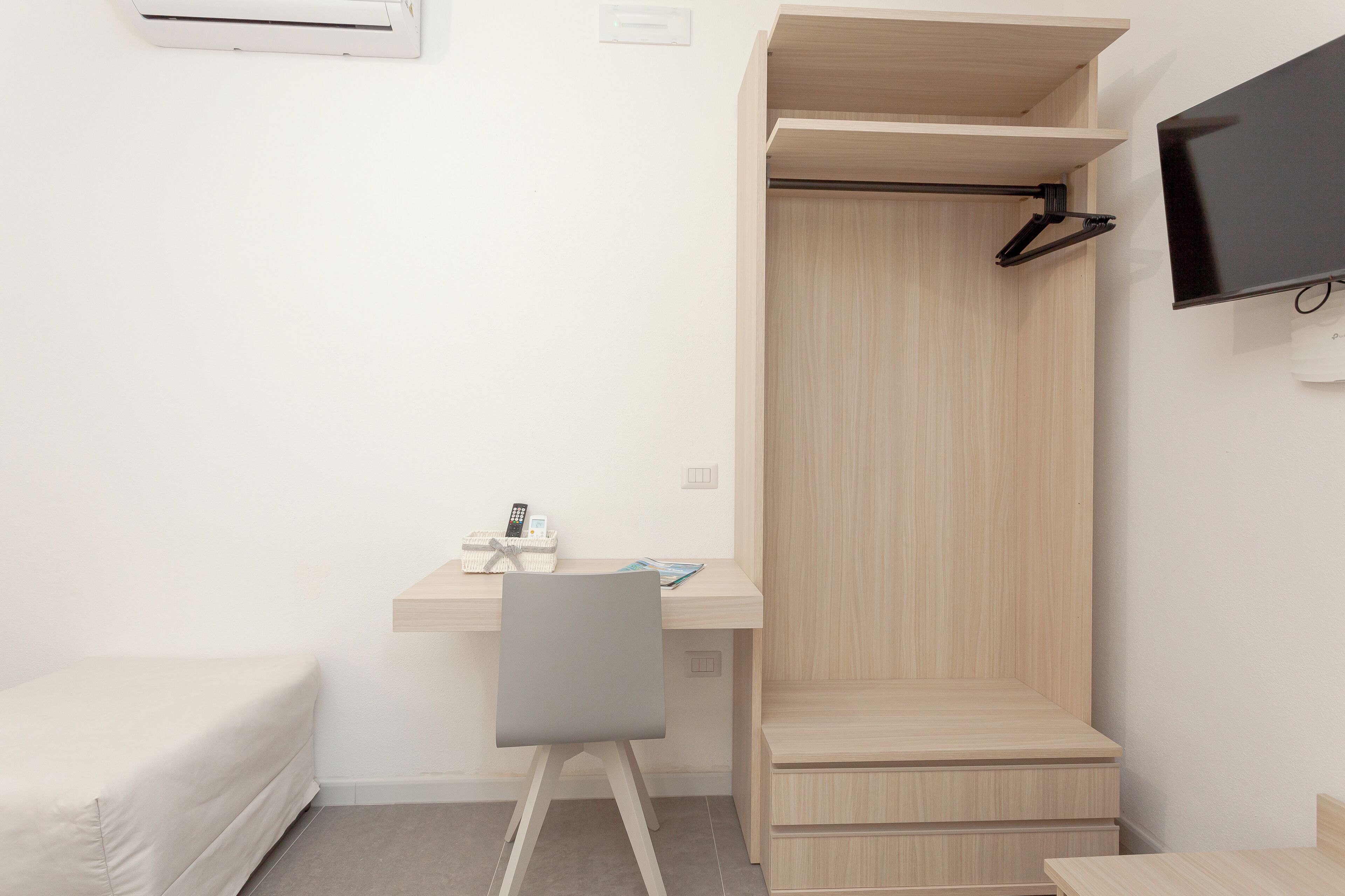 Una habitación moderna con escritorio, silla y televisor montado en la pared.