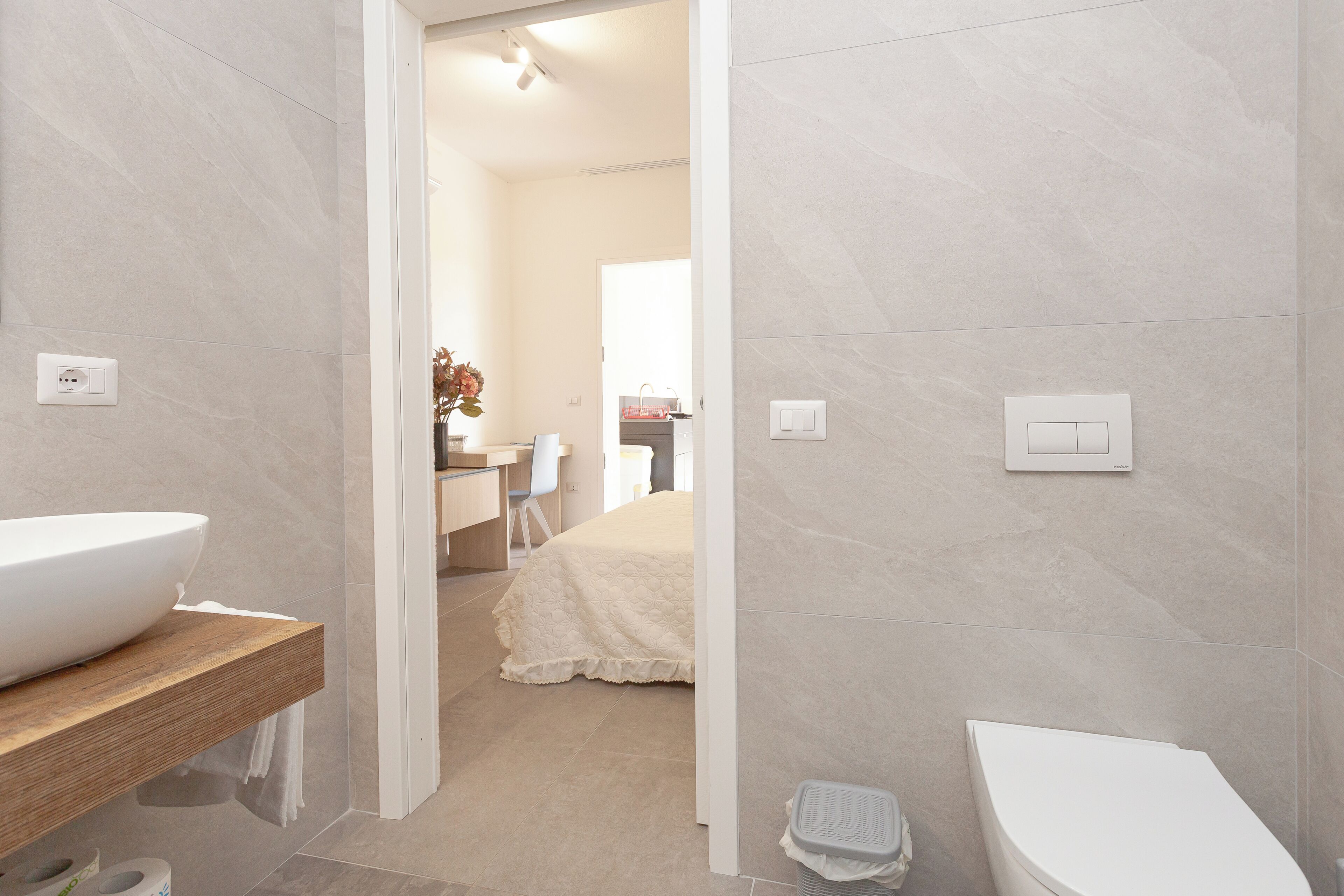 A modern bathroom with a white sink, wooden vanity, and a white toilet.