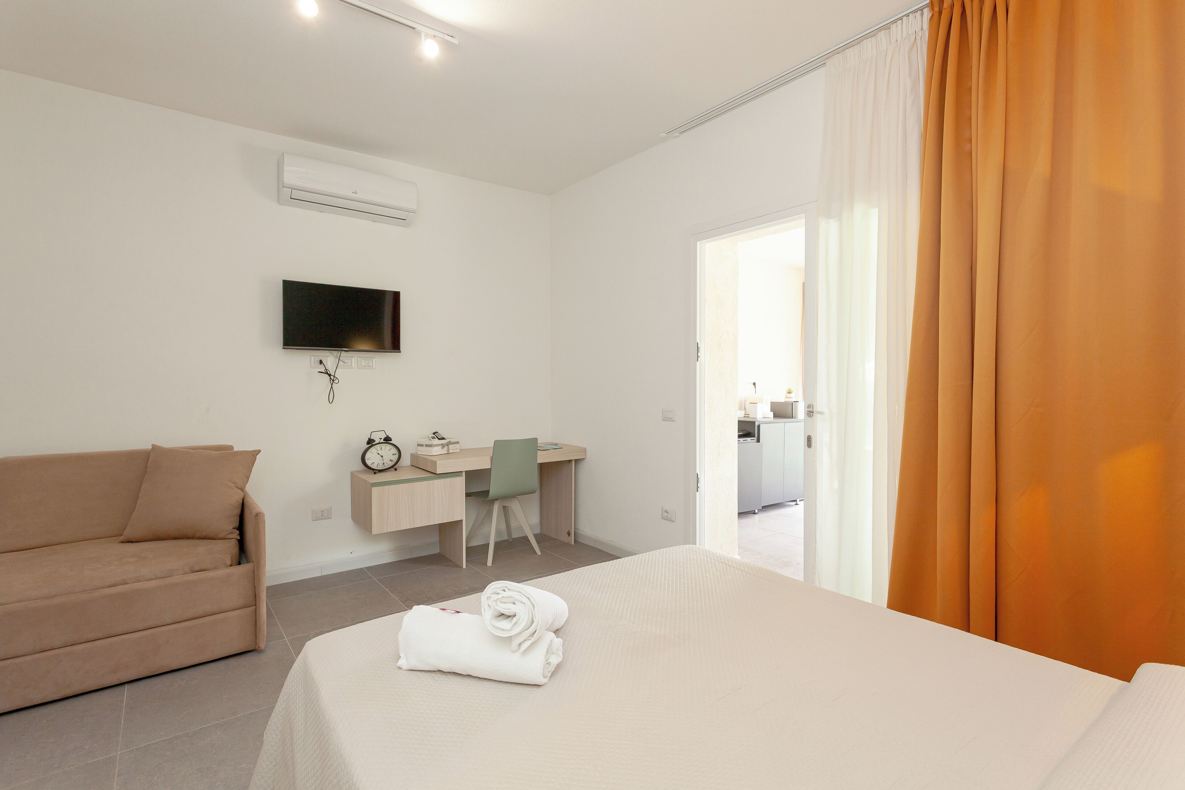 A hotel room with a bed, a desk, a chair, a television, and a window with curtains.