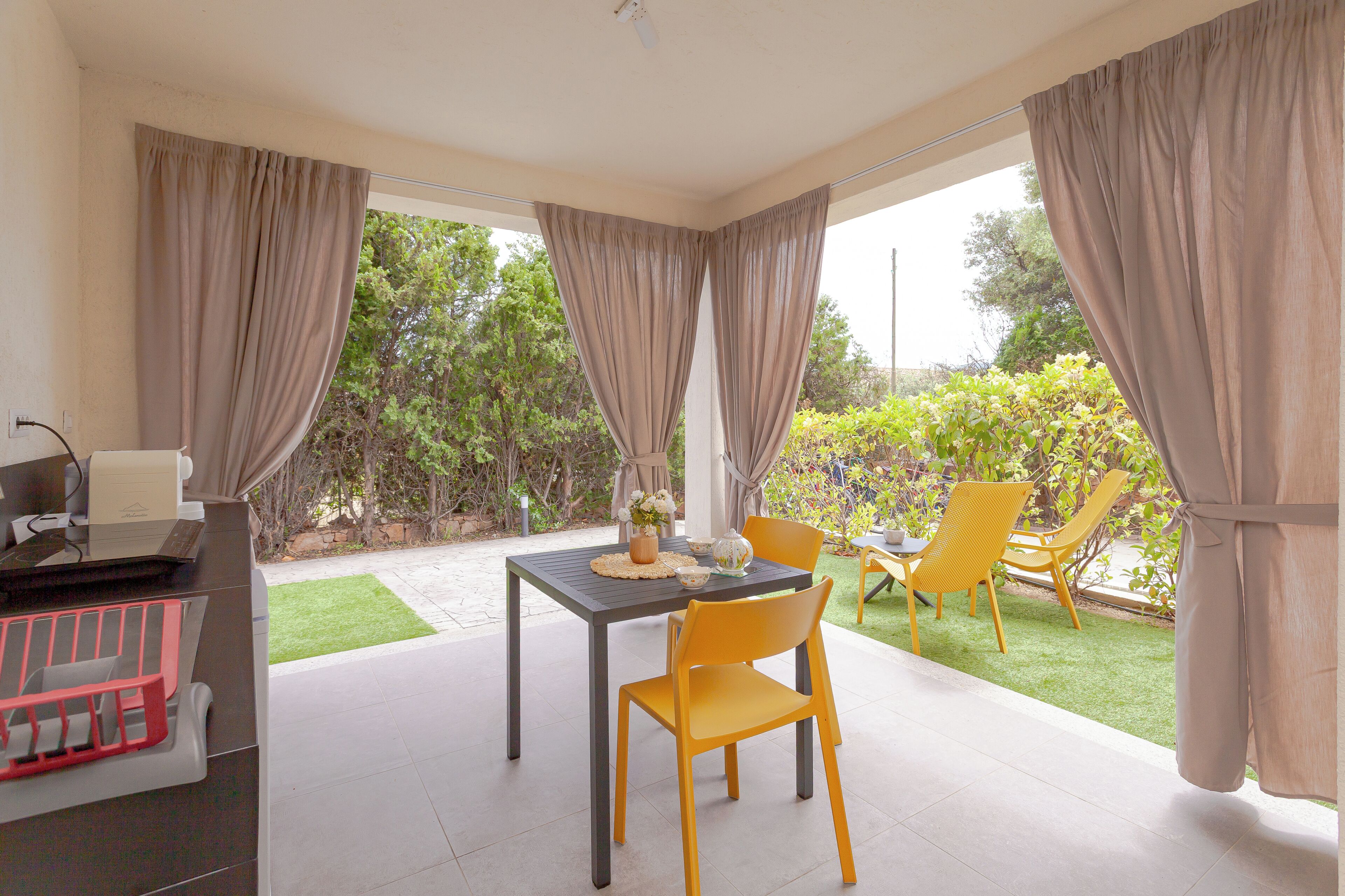 Un patio con mesa y sillas, una parrilla y vistas al jardín.