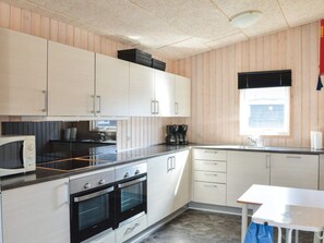 A modern kitchen with white cabinets, a microwave, a stove, and a window with blinds. - 4 Star Holiday Home in Thyboron (Thyborøn)