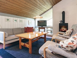 A cozy living room with a sofa, a wooden table, a television, and a fireplace.