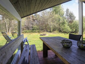 An outdoor patio with a wooden table and chairs, a wooden bench, and a view of a grassy area with trees. - 6 Person Holiday Home in Jerup (Jerup)