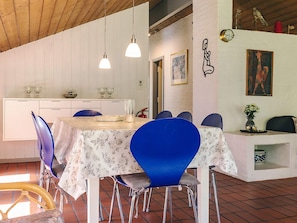 A dining area with a table set for six, surrounded by blue chairs, a white cabinet, and a red fire extinguisher.