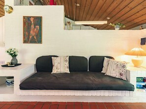 A room with a sofa, a painting, a lamp, and a small table with a vase and a plant. - 6 Person Holiday Home in Jerup (Jerup)
