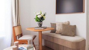Una camera moderna con una panca di legno, un tavolo rotondo con un vaso di fiori e un grande quadro appeso alla parete.