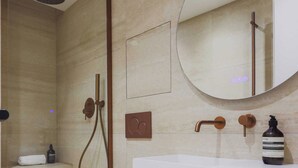 Un bagno moderno con cabina doccia in vetro, un water bianco, un mobile lavabo in legno e uno specchio rotondo.